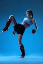 Dynamic portrait of young girl, junior MMA fighter in action, motion isolated on blue background in neon light. Concept