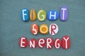 Fight for energy, social issue slogan composed with multi colored stone letters over green sand