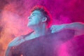 Fight for freedom. Astonished young man with stressed emotions  over pink background with clouds of smoke Royalty Free Stock Photo