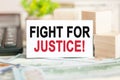 FIGHT FOR JUSTICE text on white paper, on the background of bills and wooden blocks, business concept