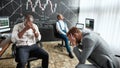 Fight together. Three traders sitting by desks in front of computer monitors while working in the office. They are