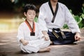 Fighter kid in Taekwondo uniform sitting concentration for training self defense body and mild