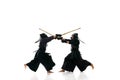 Fighters. Two men, professional kendo athletes in uniform with helmet training with bamboo shinai sword against white Royalty Free Stock Photo