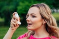 Fighting asthma and bronchitis. active cheerful beautiful young blonde woman in a pink dress using the inhaler in the Royalty Free Stock Photo