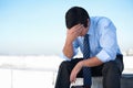 Fighting deppression. An upset corporate man sitting on the rooftop of a building with his head in his hands. Royalty Free Stock Photo