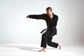 Fighting guy in black kimono fighter demonstrating karate technique on studio background with copy space Royalty Free Stock Photo