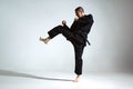 Fighting guy in black kimono fighter shows jiu jitsu technique on studio background with blank space, mix fight concept Royalty Free Stock Photo
