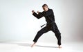 Fighting man in black kimono fighter shows karate technique on studio background with copy space, mix fight concept Royalty Free Stock Photo