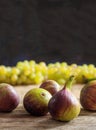 Figs and blur green grapes on wooden table. Black background Royalty Free Stock Photo