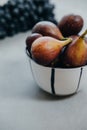 Figs in a bowl and dark grapes on a gray background. Autumn harvest Royalty Free Stock Photo