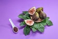 Figs, fig leaves and white spoon with jam on purple background Royalty Free Stock Photo