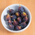 Figs fruits in a bowl on wooden background, top view Royalty Free Stock Photo