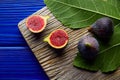 Figs raw cutted fruits and fig tree leaves on blue