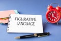 FIGURATIVE LANGUAGE - words in notebook on blue background with watch and pen Royalty Free Stock Photo