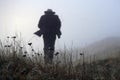 A figure blurred in the distance, wearing a long coat and trilby hat. Running away from the camera in a field