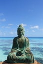 A figure of Buddha in front of a turquoise lagoon on the island of Fakarava in French Polynesia in the South Pacific; copy space