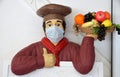 Figure cooks with fruit basket and medical mask on his face Royalty Free Stock Photo