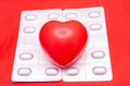 Figure of heart lies on two blisters with drugs in pills on red background. Conceptual photo for treatment methods Royalty Free Stock Photo