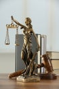 Figure of Lady Justice, gavel and books on wooden table indoors. Symbol of fair treatment under law