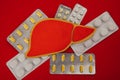 Figure liver surrounded by pills on red background