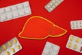 Figure liver surrounded by pills on red background. Healthcare concept