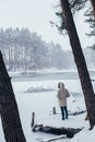 Man in winter coat at frozen snow lake in forest