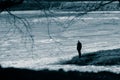 The figure of a lonely man in a black suit on a cape in the middle of a frozen pond. April, spring. Black and white toned photo