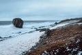 Figure of a man with a backpack in a blur in a strong wind in a storm. White sea coast. Dramatic Northern landscape