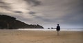 Figure of a mature woman walking along a lonely beach at sunset. Royalty Free Stock Photo