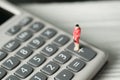 Figure miniature business woman or small people standing on calculator for money and financial business concept. Royalty Free Stock Photo