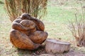 A figure of a pagan character made of wood sits on the ground next to a tree stump