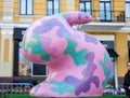 Figure of pink easter bunny with military camouflage colouring green, violet and purple spots close on background of old house. Be