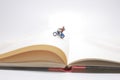 figure rides on a motorcycle over open diary book. Travel concept