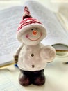 The figure of a snowman on a white table, a book in the background. Christmas decorations. New Year Royalty Free Stock Photo