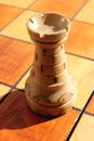 The figure of a white rook stands on a chess board