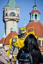 Figure of a yellow transformer robot among people