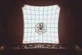 Figured ceiling in the hall of the room with a large lattice glass and expensive beautiful chandelier. square indoor texture Royalty Free Stock Photo