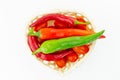 Figured wicker basket mix of cherry tomatoes large pods of hot peppers and red chili pods on white background Royalty Free Stock Photo