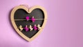 Figures of angels on clothespins, a writing Board in the form of a red heart figure on a wooden background. Pink background. Love