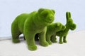 Figures of a bear, a bear cub and a donkey made of artificial grass of green color on a white background. Design
