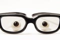 Figures eyes or eyeballs are behind black-rimmed glasses in a slightly darkened glass on a white background. Concept photo for oph