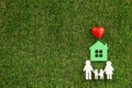 Figures of family, red heart and house on green grass, flat lay