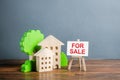 Figures of houses and an easel sign for sale. Buying and selling real estate, hot offers and property valuation. Smart investments Royalty Free Stock Photo