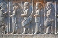 Figures of soldiers in ancient costumes on the destroyed stone bas-relief Royalty Free Stock Photo