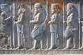 Figures of soldiers in ancient costumes on the destroyed stone bas-relief