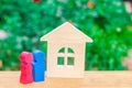 Figures of a young couple in love are standing near a wooden house. The concept of affordable and cheap housing for young families