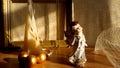 figurine of an angel, golden Christmas balls, pyramid candle on a yellow background