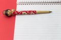 Figurine ball point pen on blank note pad with red background - Royalty Free Stock Photo