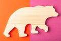 A figurine of a bear carved from solid pine by a hand jigsaw. On a multi-colored background