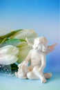 figurine of a cute angel made of white ceramics and a small rabbit next to a bouquet of white tulips Royalty Free Stock Photo